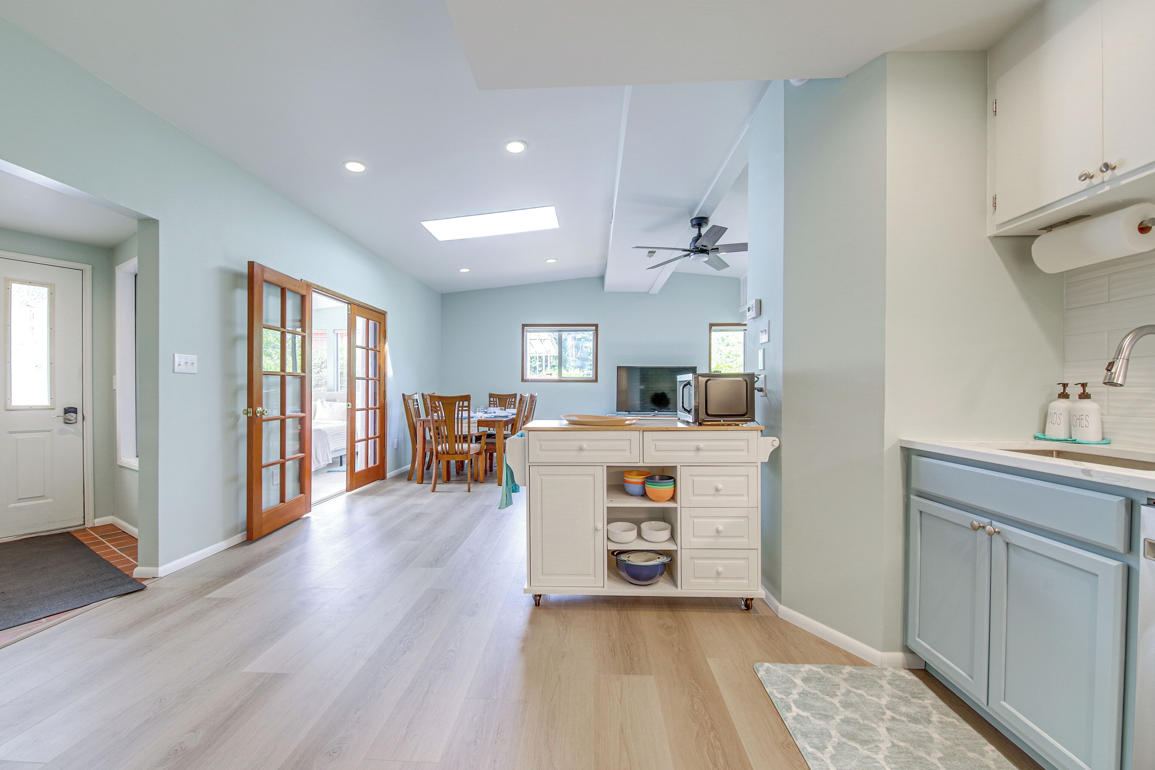 Une cuisine spacieuse avec un coin repas, un plancher en bois et un ventilateur de plafond.