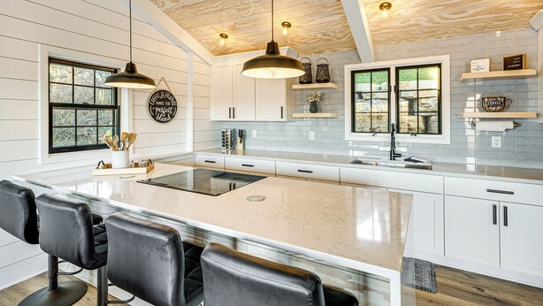 A modern kitchen with a large island, white cabinetry, and pendant lighting. - Canoes & Dock: Waterfront Retreat on Lake Beulah! (East Troy)