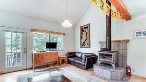 A living room with a fireplace, a wooden table, a leather sofa, and a television. - 6 Mi to Downieville Downhill: Cabin w/ Mtn Views (Sierra City)