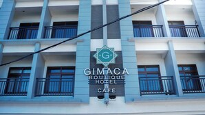 Un edificio con un letrero que dice 'GIMACA Boutique Hotel & Cafe'.