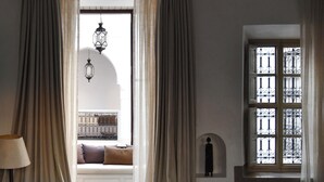 A bedroom with a large window, a bed, a nightstand, a lamp, and a view of a balcony. - Riad Berbere Marrakech (Marrakech)