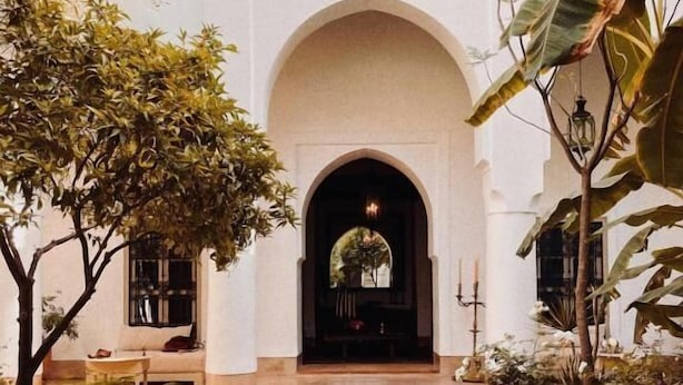 A courtyard with a pool, a seating area, and a view of a building through an arched doorway. - Riad Berbere Marrakech (Marrakech)