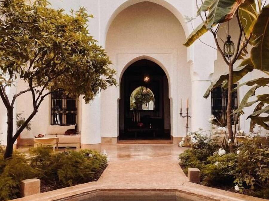Ein Innenhof mit Pool, einer Sitzgelegenheit und Blick auf ein Gebäude durch einen Bogen.