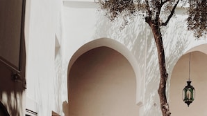 A corridor with arches, potted plants, and a hanging lantern. - Riad Berbere Marrakech (Marrakech)
