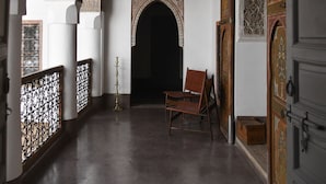 A corridor with ornate arches, a hanging lantern, and a wooden chair. - Riad Berbere Marrakech (Marrakech)
