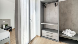 A modern bedroom with a bed, a bedside table, a wardrobe, and a window with curtains. - Rome Experience (Rome)