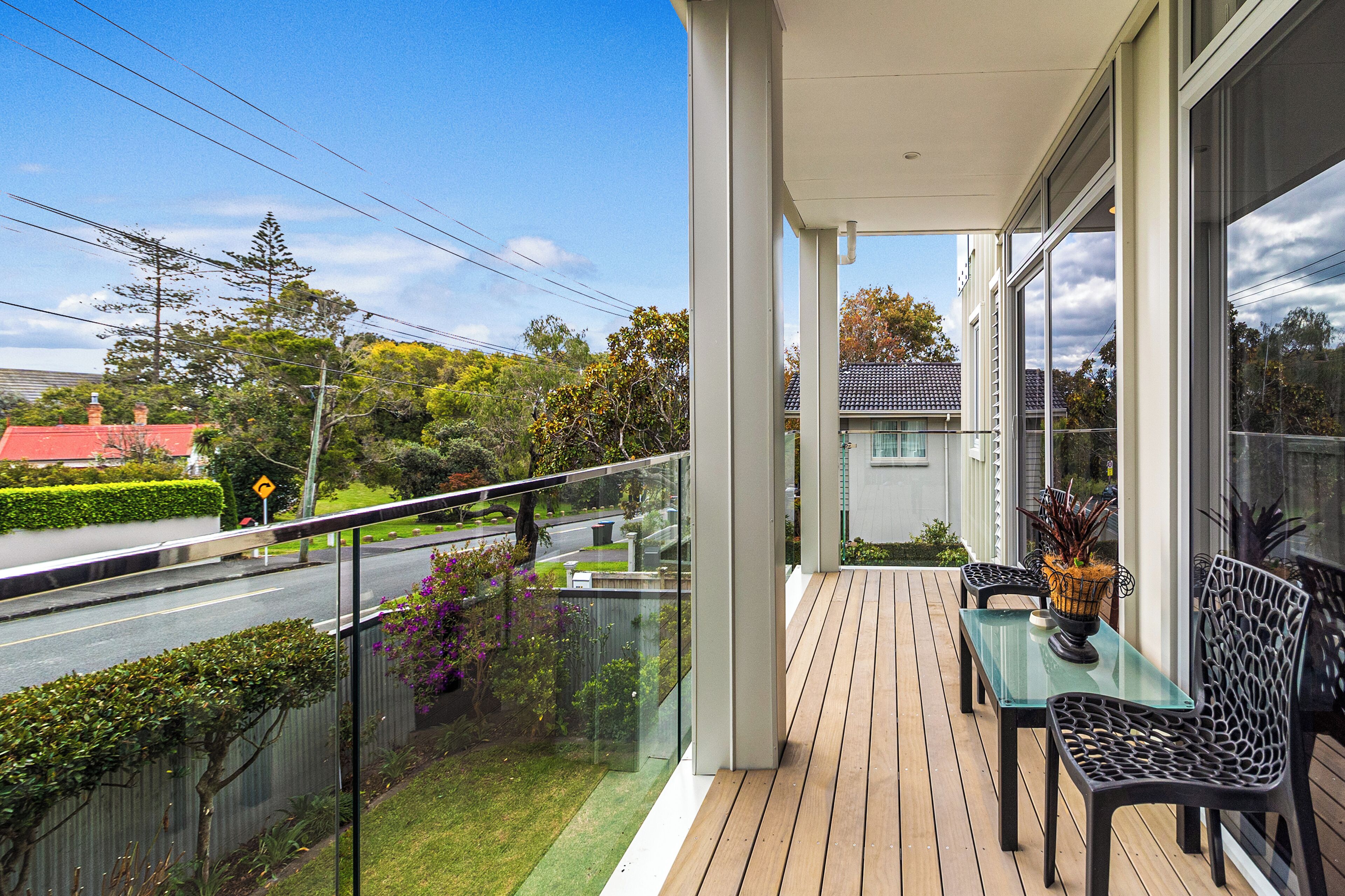 Un balcon doté d’une balustrade en verre, d’une table et de deux chaises.