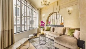 Una sala de estar moderna con un ventanal grande, un sofá, una mesa de centro y una araña.