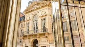 Un edificio clásico con detalles arquitectónicos ornamentales, incluyendo un balcón con intrincada rejería y un arco central.