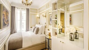 Un dormitorio lujoso con una cama grande, una araña, un espejo y vistas de la ciudad.