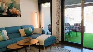 Ein Wohnzimmer mit einem blauen Sofa, einem runden Couchtisch und einem Wandbild mit Lotusblumen.