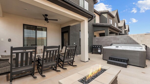 Un espacio al aire libre con patio, una chimenea, asientos y un jacuzzi.
