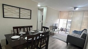 Un espace repas comprenant une table et des chaises en bois, un canapé et une vue sur l’extérieur.