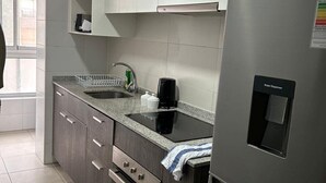 Une cuisine moderne avec des meubles gris, un réfrigérateur en acier inoxydable, un four encastré et un plan de travail en granit.