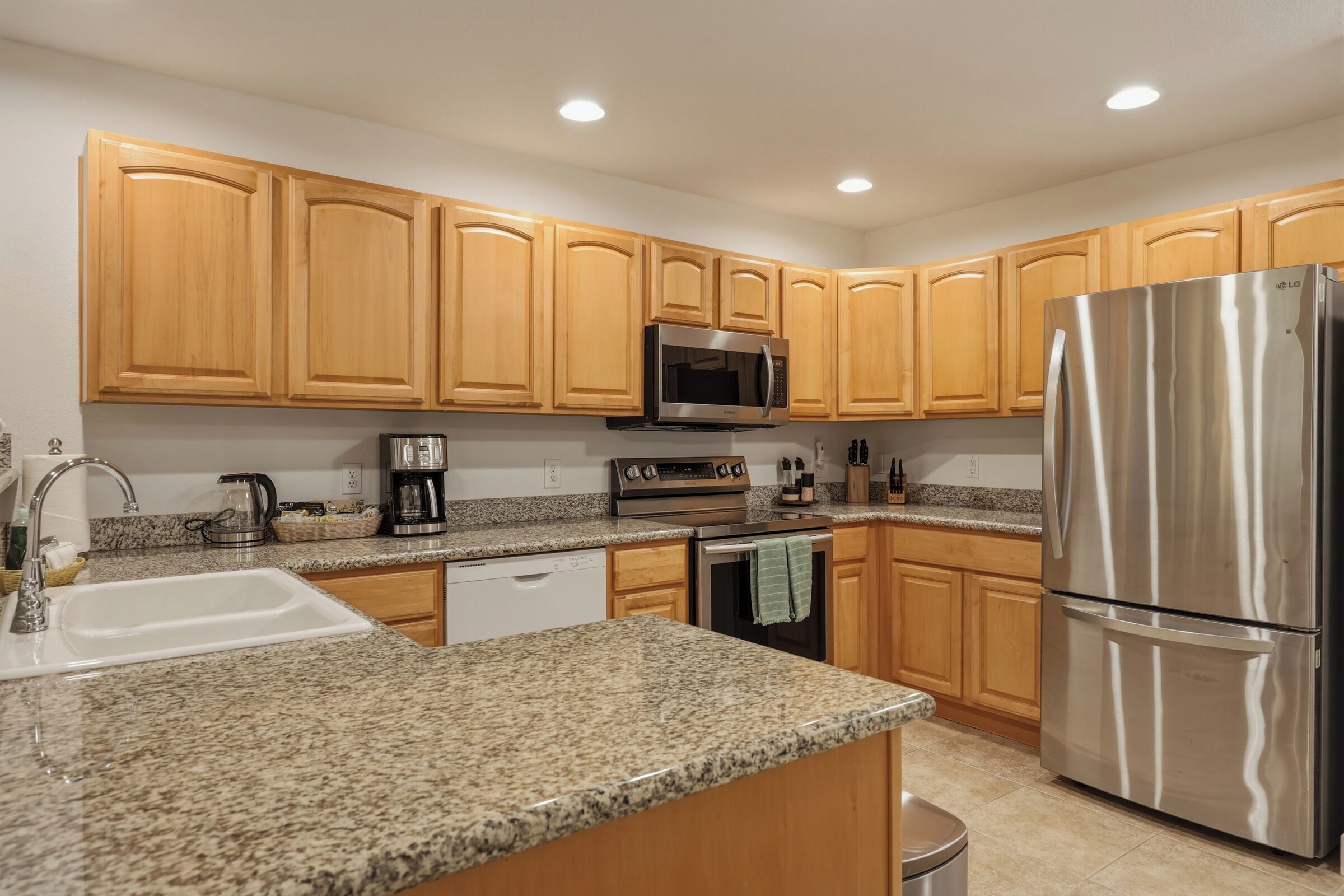 A kitchen with granite countertops, wooden cabinets, stainless steel appliances, and a dishwasher.