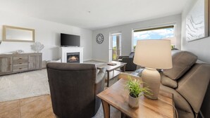 Ein Wohnzimmer mit Kamin, Fernseher, Sofa, Couchtisch und einer Lampe.