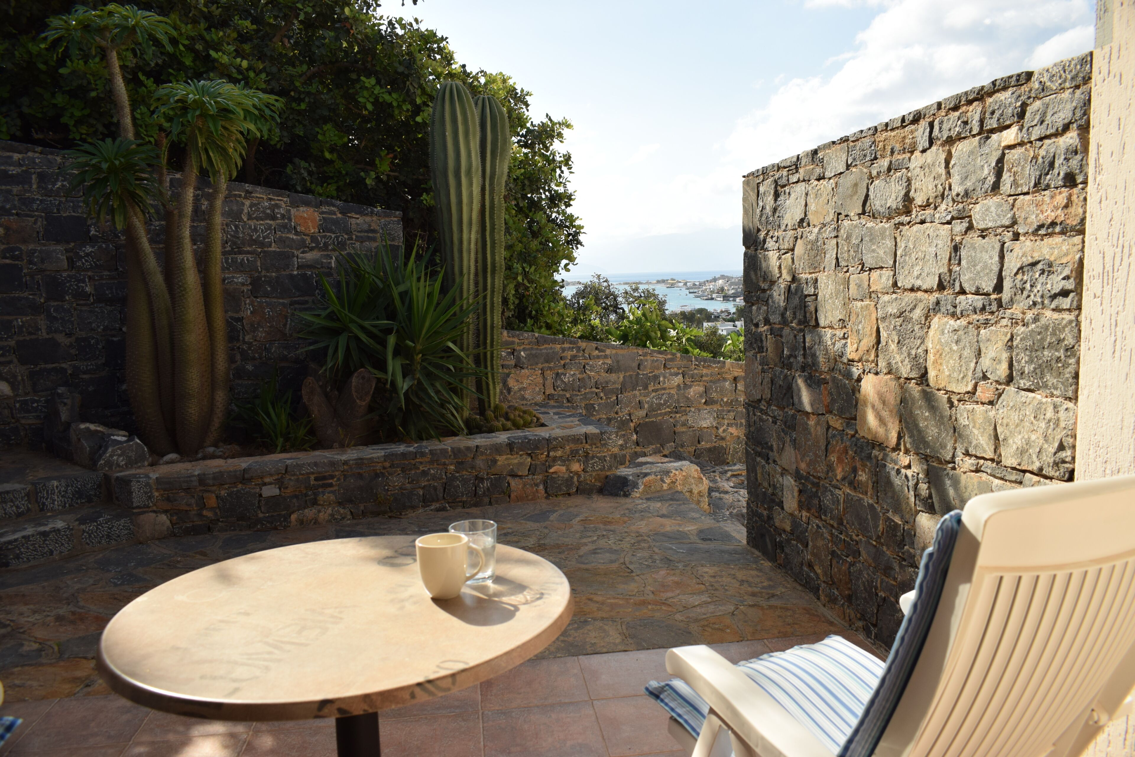 A stone wall, a cactus, and a view of the sea.