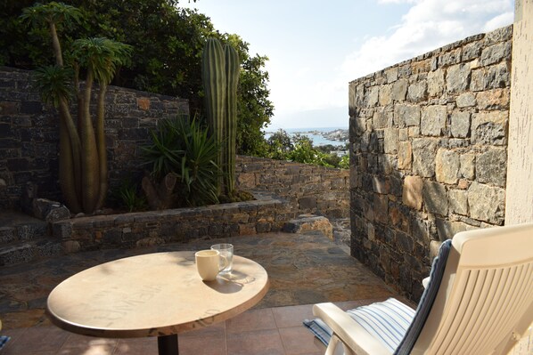 A stone wall, a cactus, and a view of the sea.