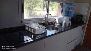 Une cuisine équipée d’un évier, d’un distributeur d’eau, d’un grille-pain et d’un égouttoir à vaisselle.
