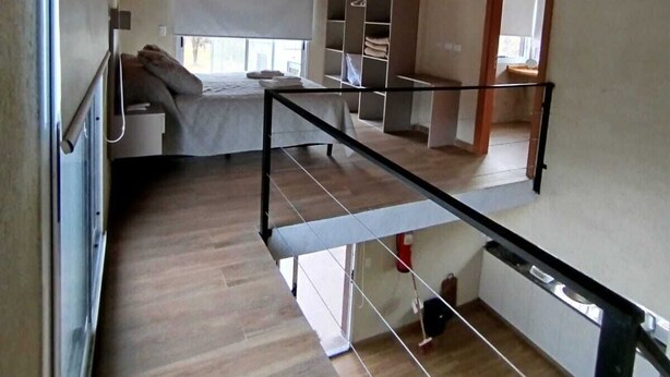Un vaste espace de vie de style loft, doté d’un plafond haut, de poutres apparentes, d’une mezzanine et d’une grande fenêtre laissant entrer la lumière naturelle.