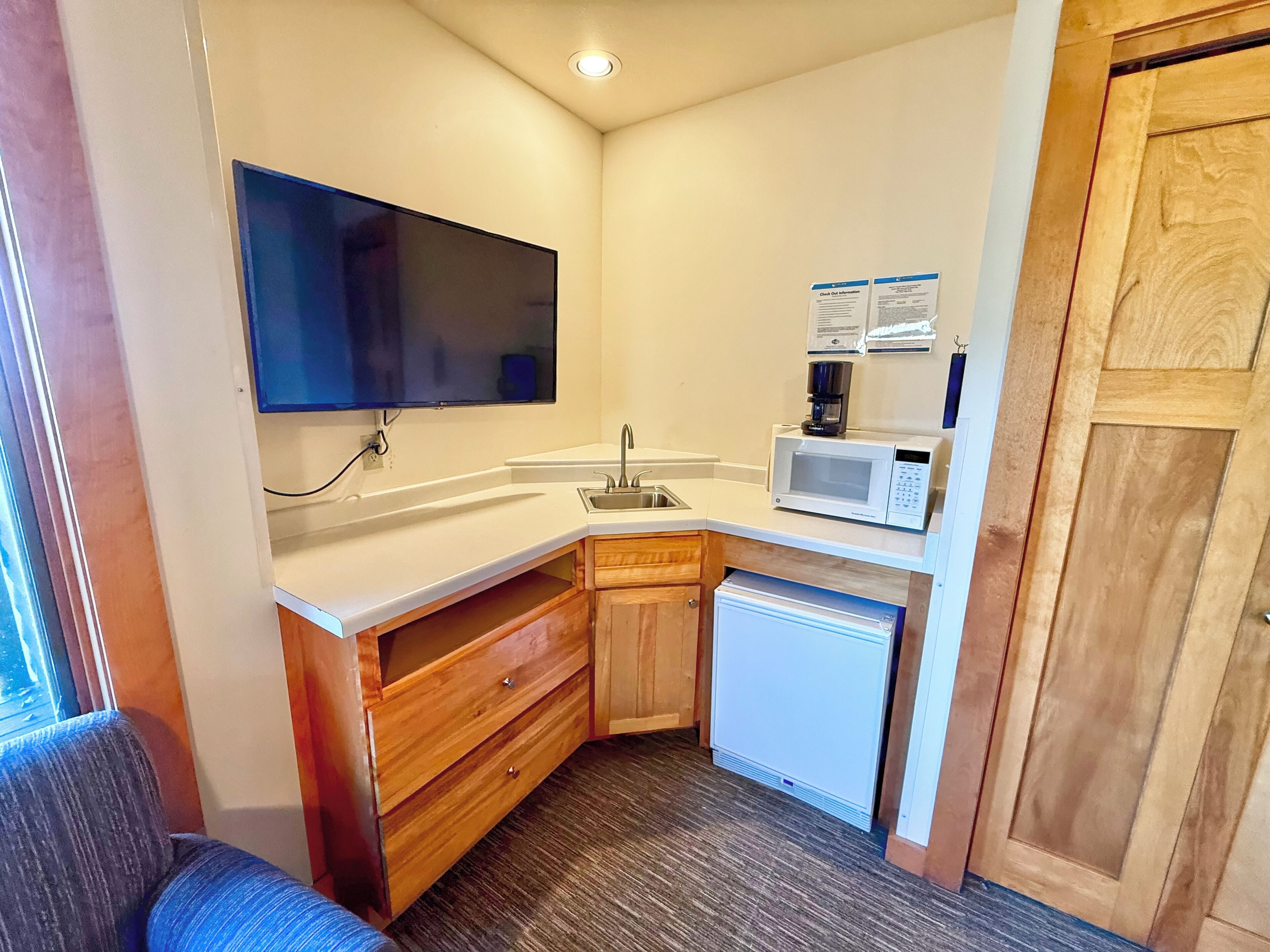A compact kitchenette with a flat-screen TV, a microwave, a coffee maker, and a small refrigerator.