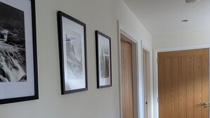 Un corridoio con quadri appesi alle pareti, un termosifone e una porta in legno in fondo.