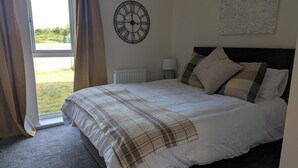 Una camera da letto con un letto, una sveglia, un termosifone e vista sull'esterno.