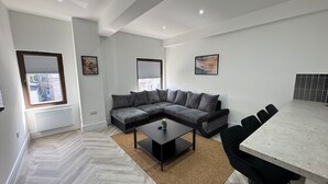 Una sala de estar moderna con un sofá modular, una mesa de centro, una mesa de comedor con sillas y obras de arte en las paredes.
