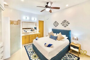 A bedroom with a bed, bedside table, nightstand, and a ceiling fan.