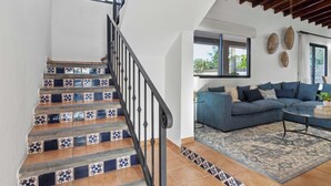 Eine Treppe mit gemusterten Fliesen, ein blaues Sofa und ein Deckenventilator in einem Wohnbereich.