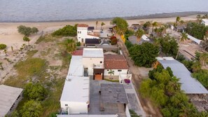 Oversigtsbillede af et kystnære boligområde med huse, en strand og palmetræer.