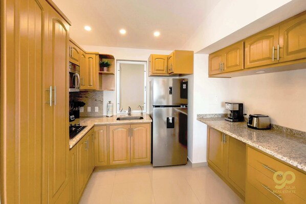 A kitchen with wooden cabinets, stainless steel appliances, a sink, and a countertop with a coffee maker and toaster.