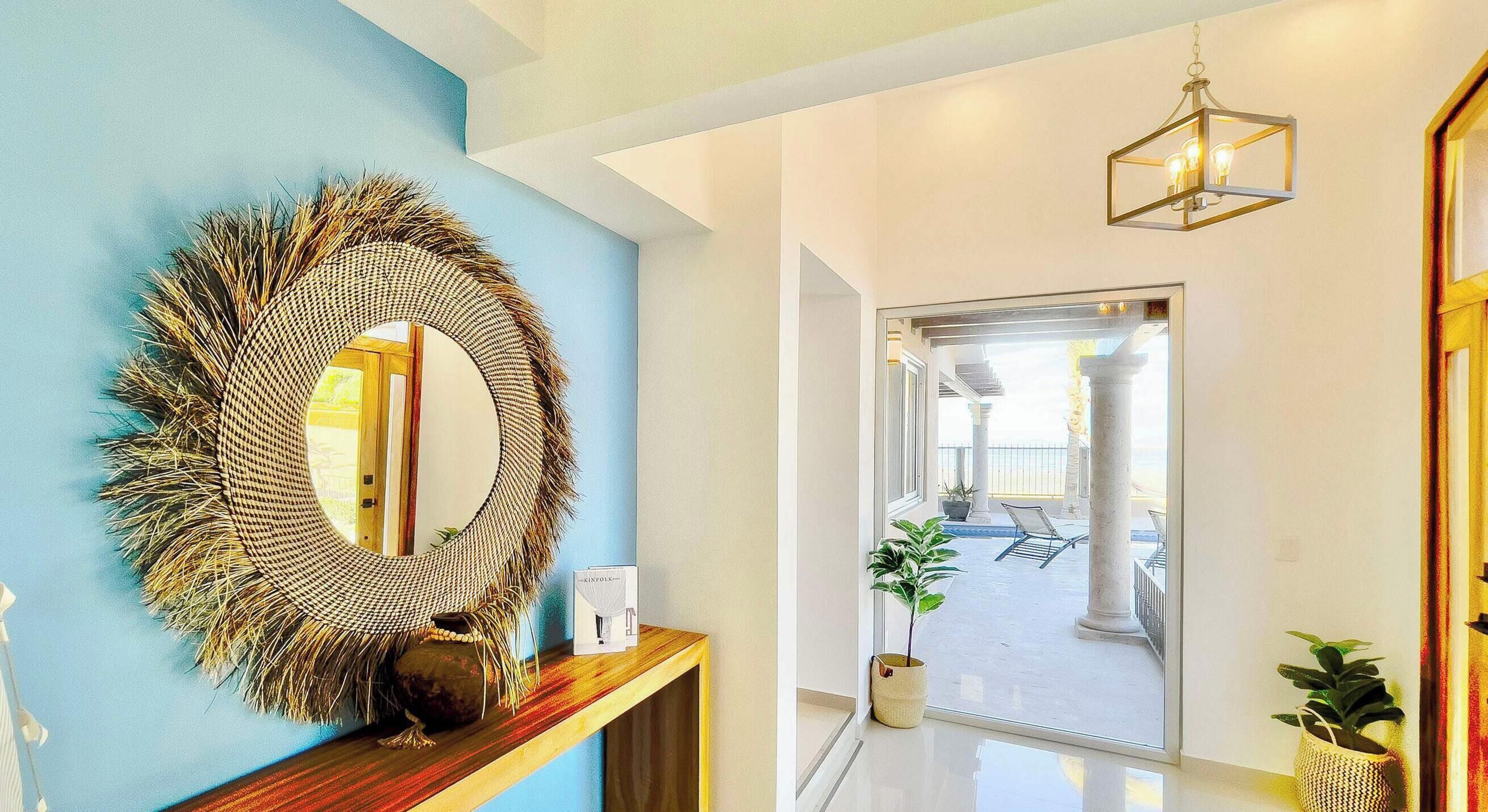 Un couloir avec un grand miroir, une console en bois et un luminaire suspendu.