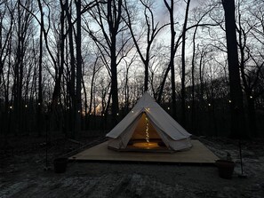 A tent set up on a wooden platform surrounded by trees.