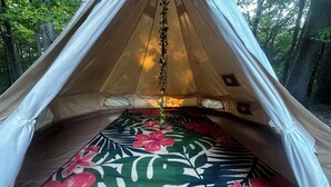 Uma tenda com chão estampado em flor, uma corrente pendurada e uma pequena janela.