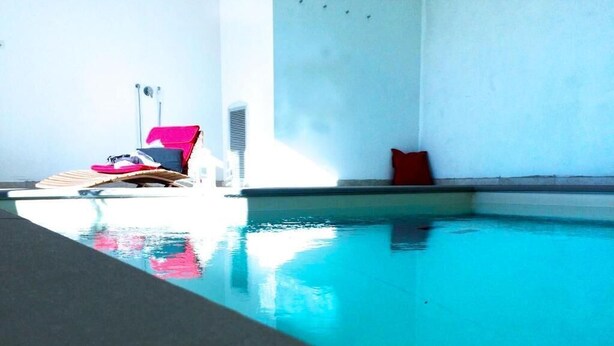 Una piscina con una silla de descanso y un cojín rojo.