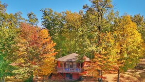 A cabin with a porch, surrounded by trees with autumn foliage.