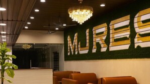 A lobby with a reception desk, seating area, and a wall with the word "MUREX" in large letters. - MJ Resort (Port Blair)
