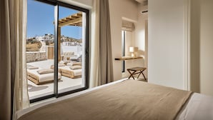 Et hotelværelse med en stor skydedør, der fører ud til en balkon med udsigt til bygninger og en stenvæg.
