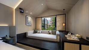 A modern hotel room with a sofa bed, a desk with tea set, a projector, and a view of buildings through large windows. - Healing mind International Hotel Guangzhou Tianhe Sports Center Linhexi Metro Station Branch (Guangzhou)