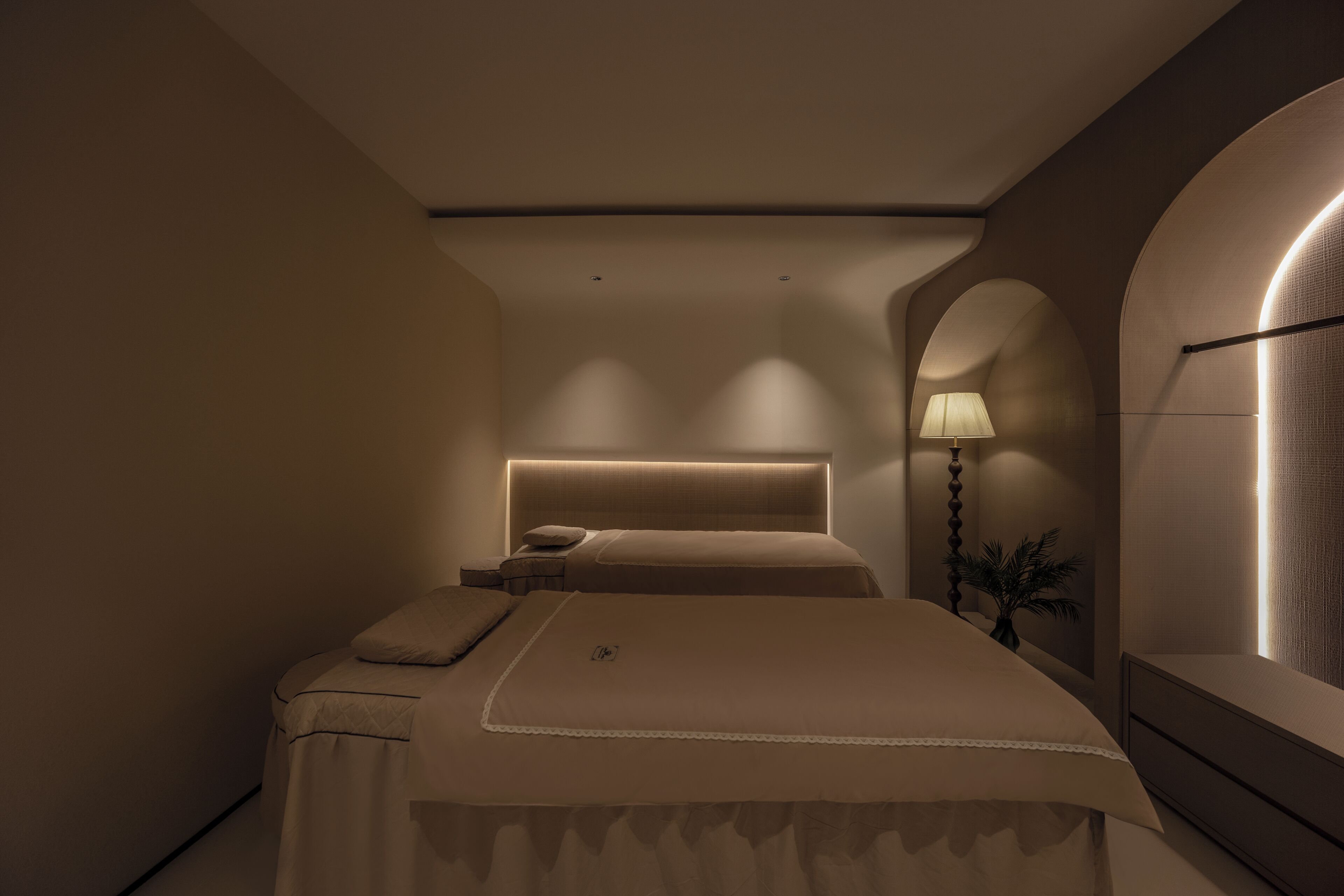 A modern bedroom with a large bed, bedside tables, a lamp, and a mirror.