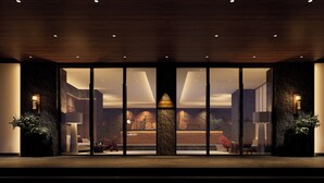 A modern hotel lobby with a stone column, wooden ceiling, and large glass doors leading to the interior. - Healing mind International Hotel Guangzhou Tianhe Sports Center Linhexi Metro Station Branch (Guangzhou)