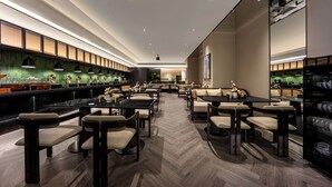 A modern restaurant with a long counter, multiple tables, and chairs. - Healing mind International Hotel Guangzhou Tianhe Sports Center Linhexi Metro Station Branch (Guangzhou)