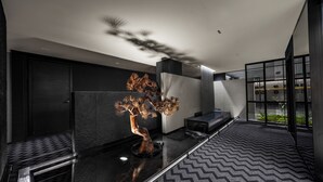 A modern interior with a central sculptural tree, a patterned floor, and a minimalist seating area. - Healing mind International Hotel Guangzhou Tianhe Sports Center Linhexi Metro Station Branch (Guangzhou)