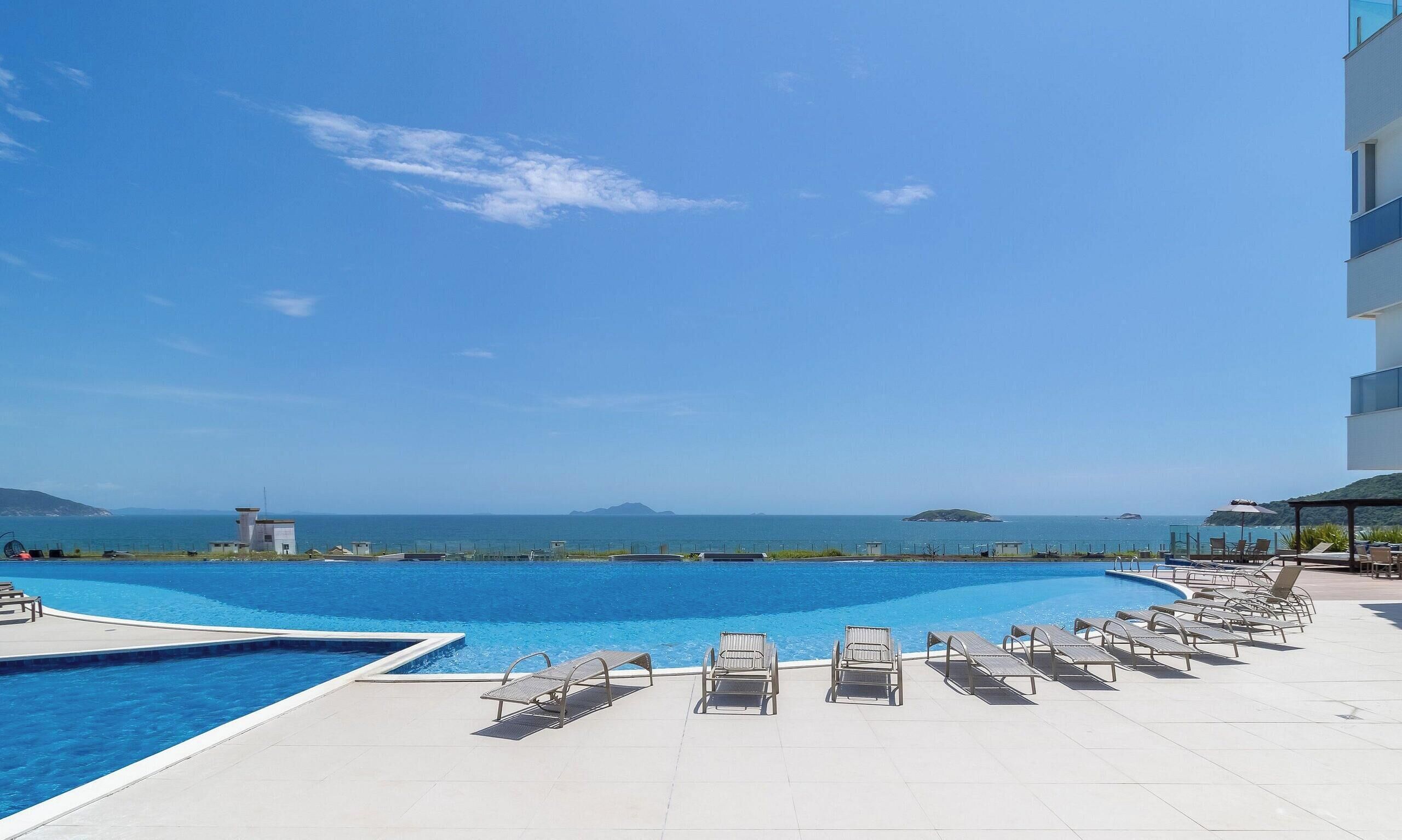 Una piscina con sillas de descanso y vistas al mar.