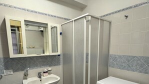 A bathroom with a sink, mirror, shower enclosure, and a washing machine. - Comfortable and quiet house near the sea (Oliveri)