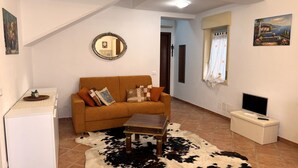 A living room with a sofa, a coffee table, a television, and a cowhide rug. - Comfortable and quiet house near the sea (Oliveri)