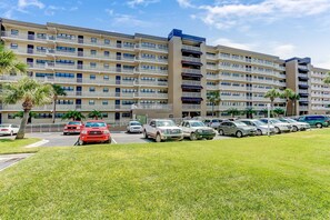 Ein mehrstöckiges Hotel mit Parkplatz, Palmen und blauem Himmel.