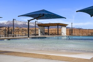 A swimming pool with a mountain backdrop, shaded areas, and a fenced perimeter. - The Cactus Casa 4 Bedroom Townhouse (Washington)