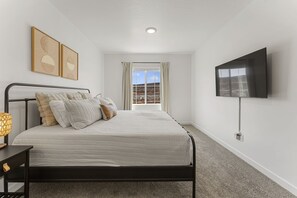 A bedroom with a bed, a TV, and a window with curtains. - The Cactus Casa 4 Bedroom Townhouse (Washington)